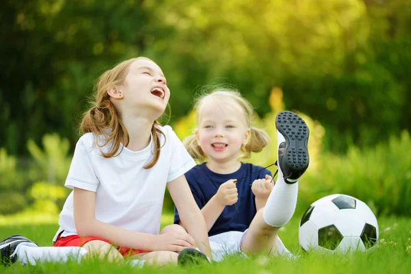 Dos monas hermanitas divirtiéndose jugando un partido de fútbol en el soleado día de verano. Actividades deportivas para niños . — Foto de Stock