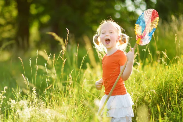 Adorable niñita atrapando mariposas y bichos con su red de pala. Niño explorando la naturaleza en el soleado día de verano . — Foto de Stock