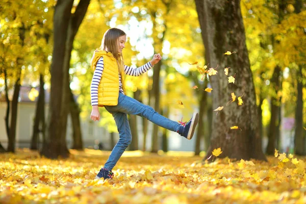 Schattig jong meisje plezier op mooie herfst dag. Gelukkig kind spelen in herfst Park. Kid verzamelen gele val loof. — Stockfoto