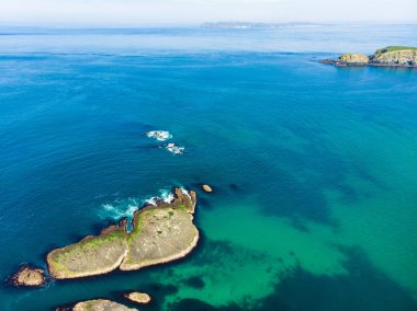 County Antrim Causeway Coast boyunca Ballintoy limanında canlı zümrüt yeşili su. Kuzey İrlanda'nın engebeli kıyıları.