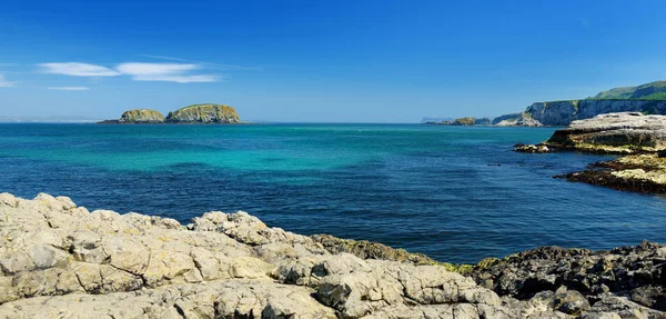 Água verde-esmeralda vívida no porto de Ballintoy ao longo da Costa da Causeway, no Condado de Antrim. Costa acidentada da Irlanda do Norte . — Fotografia de Stock