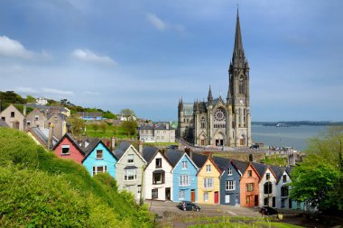 Cobh, County Cork, İrlanda liman kasabasında arka planda St Colman Katedrali ile renkli satır evler