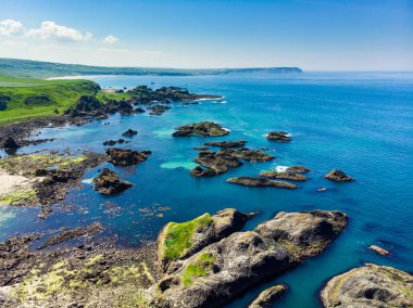 County Antrim Causeway Coast boyunca Ballintoy limanında canlı zümrüt yeşili su. Kuzey İrlanda'nın engebeli kıyıları.