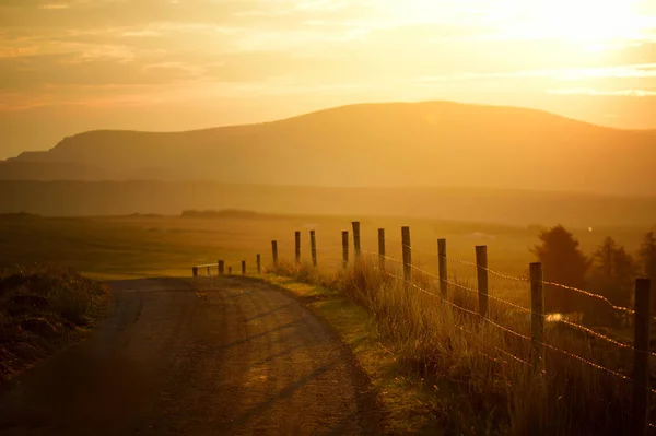 Ηλιοβασίλεμα στο Κονεμάρα. Γραφική ιρλανδική ύπαιθρο δρόμος που οδηγεί σε μαγευτικά βουνά, κομητεία Γκάλγουεϊ, Ιρλανδία. — Φωτογραφία Αρχείου