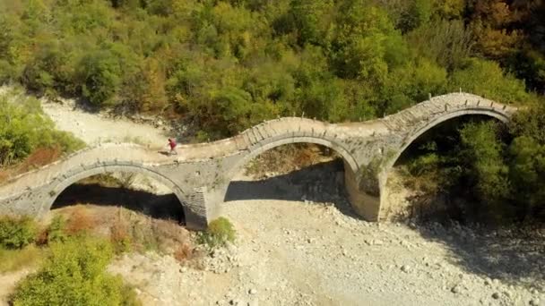 Aerial view of a tourist crossing Plakidas arched stone bridge of Zagori region — Stock Video