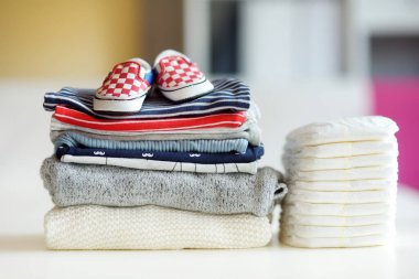 Bebek kıyafetleri, tek kullanımlık bebek bezleri ve küçük ayakkabılar. Ebeveyn masrafları konsepti. Bebek bütçesi hazırlıyorum. Yeni doğmuş bir bebek için para biriktiriyorum. Yeni bir bebek için bütçe ayırıyorum..