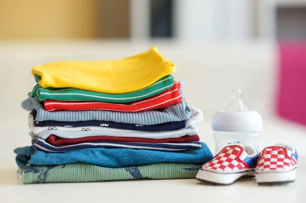 Ein Stapel Babykleidung Eine Fütterungsflasche Und Kleine Neugeborenenschuhe Erziehungskostenkonzept Die — Stockfoto