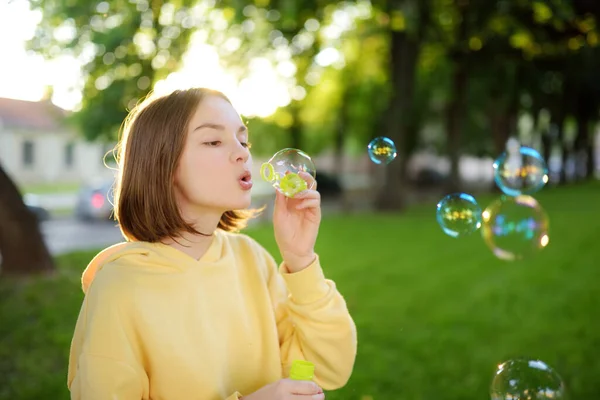 きれいな10代の女の子が日没にシャボン玉を吹いている 夏に公園で遊んでいる子供 子供のための面白い活動 — ストック写真