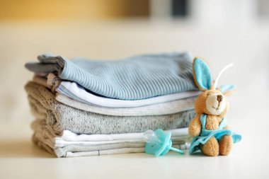 Bir yığın bebek kıyafeti, emzik ve oyuncak tavşan. Ebeveyn masrafları konsepti. Bebek bütçesi hazırlıyorum. Yeni doğmuş bir bebek için para biriktiriyorum. Yeni bir bebek için bütçe ayırıyorum..