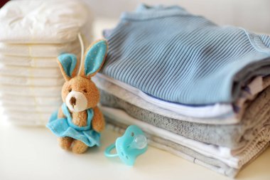 Bebek kıyafetleri, bebek bezleri, emzik ve oyuncak tavşan. Ebeveyn masrafları konsepti. Bebek bütçesi hazırlıyorum. Yeni doğmuş bir bebek için para biriktiriyorum. Yeni bir bebek için bütçe ayırıyorum..