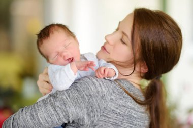 Annesinin kollarında küçük tatlı bir erkek bebek. Evde küçük bir bebeğin portresi. Annesi tarafından kucaklanan sevimli bir oğul. Yeni neşe demeti.