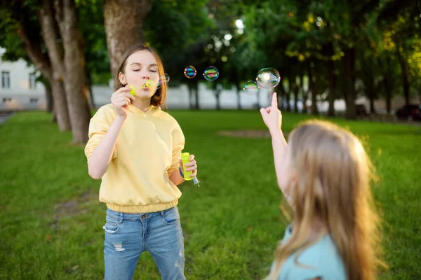 きれいな10代の女の子が日没にシャボン玉を吹いている 夏に公園で遊ぶ子供たち 子供のための面白い活動 — ストック写真