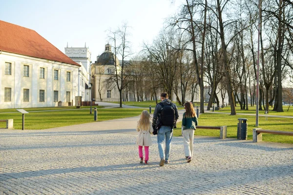 2人のかわいい女の子と彼らの父親は 暖かく晴れた春の日にリトアニアのヴィリニュスの通りを観光します — ストック写真