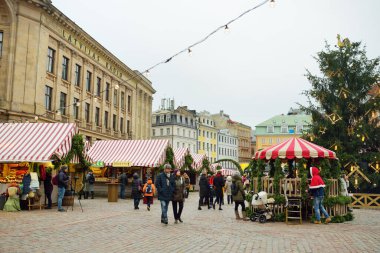 RIGA, LATVIA - 19 Aralık 2019 İnsanlar Riga 'nın en otantik Noel pazarının keyfini çıkarırken düzinelerce el işi ve gıda tezgahı sunuyorlar..