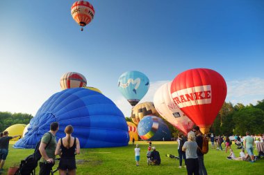 VILNIUS, LITHUANIA - 3 Temmuz 2020: Güneşli yaz akşamlarında Vilnius şehrindeki Vingis parkından havalanan renkli sıcak hava balonları. Bir sürü insan balonların uçuşunu izliyor..