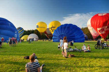 VILNIUS, LITHUANIA - 3 Temmuz 2020: Güneşli yaz akşamlarında Vilnius şehrindeki Vingis parkından havalanan renkli sıcak hava balonları. Bir sürü insan balonların uçuşunu izliyor..