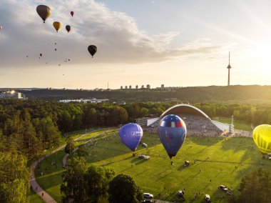 VILNIUS, LITHUANIA - 3 Temmuz 2020: Güneşli yaz akşamlarında Vilnius şehrindeki Vingis parkından havalanan renkli sıcak hava balonları. Bir sürü insan balonların uçuşunu izliyor..