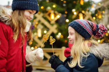 Riga, Letonya 'da geleneksel Noel fuarında horoz şeklinde lolipopları olan iki sevimli kız kardeş. Çocuklar Noel pazarında tatlı, şeker ve zencefilli çöreğin tadını çıkarıyorlar. Aile ve çocuklarla kış zamanı..