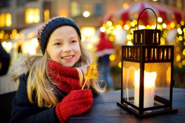 Riga, Letonya 'da geleneksel Noel fuarında horoz şeklinde lolipop yiyen tatlı genç bir kız. Çocuk Noel pazarında tatlı, şeker ve zencefilli çöreğin tadını çıkarıyor. Aile ve çocuklarla kış zamanı..
