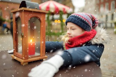 Riga, Letonya 'da geleneksel Noel fuarında fenere bakan sevimli genç bir kız. Çocuklar Noel pazarında tatlı, şeker ve zencefilli çöreğin tadını çıkarıyorlar. Aile ve çocuklarla kış zamanı..