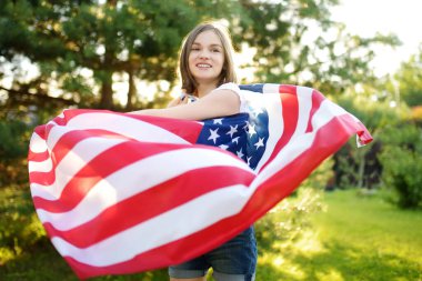 Güzel bir yaz gününde elinde Amerikan bayrağı tutan sevimli genç bir kız. Bağımsızlık Günü konsepti. Ulusal bayramı kutlayan çocuk. Anma Günü.