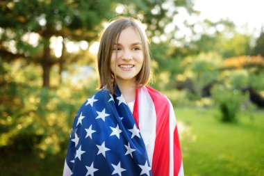 Güzel bir yaz gününde elinde Amerikan bayrağı tutan sevimli genç bir kız. Bağımsızlık Günü konsepti. Ulusal bayramı kutlayan çocuk. Anma Günü.