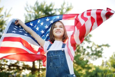 Güzel bir yaz gününde elinde Amerikan bayrağı tutan sevimli genç bir kız. Bağımsızlık Günü konsepti. Ulusal bayramı kutlayan çocuk. Anma Günü.