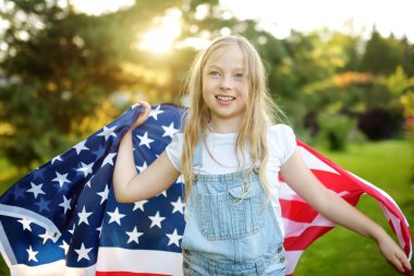 Güzel bir yaz gününde elinde Amerikan bayrağı tutan sevimli genç bir kız. Bağımsızlık Günü konsepti. Ulusal bayramı kutlayan çocuk. Anma Günü.