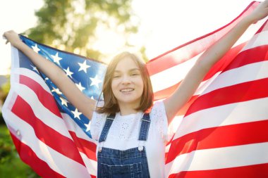 Güzel bir yaz gününde elinde Amerikan bayrağı tutan sevimli genç bir kız. Bağımsızlık Günü konsepti. Ulusal bayramı kutlayan çocuk. Anma Günü.