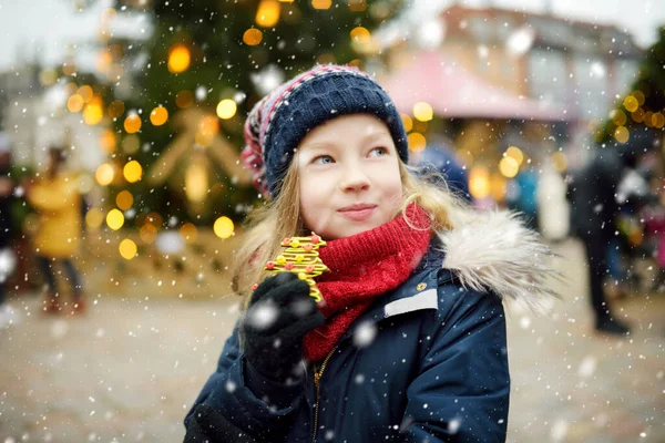ラトビアのリガで伝統的なクリスマスフェアでジンジャーブレッドクッキーを持っているかわいい女の子 クリスマスマーケットでお菓子やキャンディー ジンジャーブレッドを楽しむ子供たち 家族や子供と冬の時間 — ストック写真