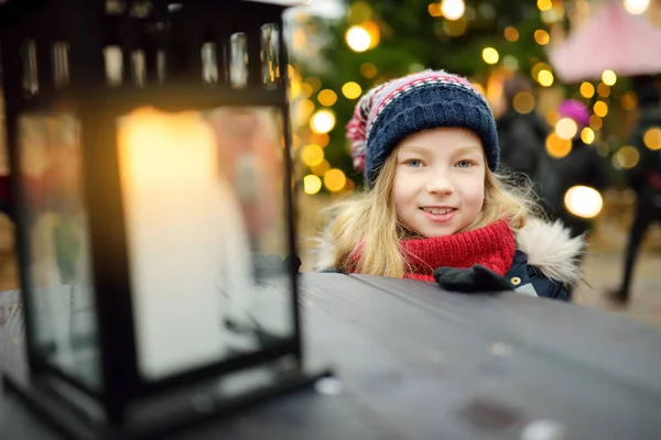 ラトビアのリガで行われる伝統的なクリスマス フェアの提灯を見ているかわいい若い女の子 クリスマスマーケットでお菓子やキャンディー ジンジャーブレッドを楽しむ子供たち 家族や子供と冬の時間 — ストック写真