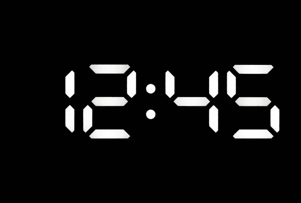 Real white led digital clock on a black background showing time 12:45