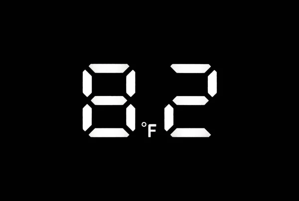 Real white led digital clock on a black background showing temperature 82F