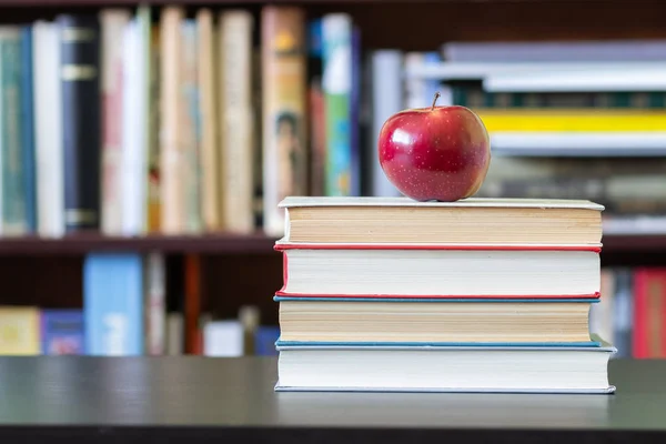 本棚の背景の上にアップルと書籍のスタック — ストック写真