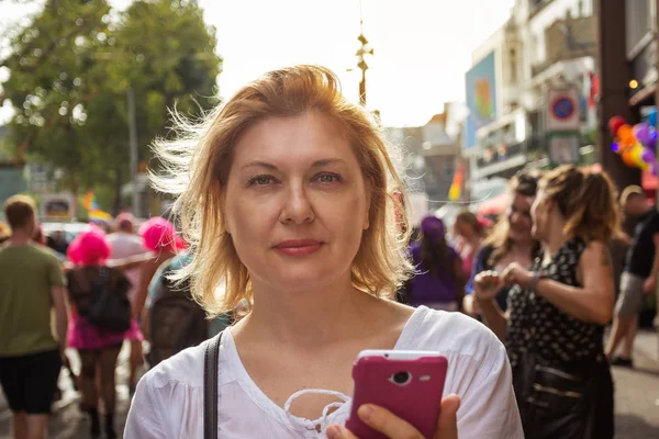 近代的な都市の通りの背景に手に携帯電話を持つ美しい大人の女性の肖像画 — ストック写真