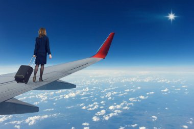 Genç bir kadın ile bir çantayla uçan bir uçağın kanadında geldi ve sersem gökyüzünde parlak yıldız bakar.