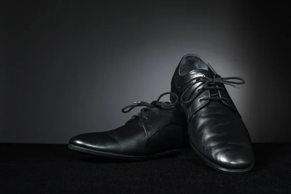 Black classic men's shoes on dark background.