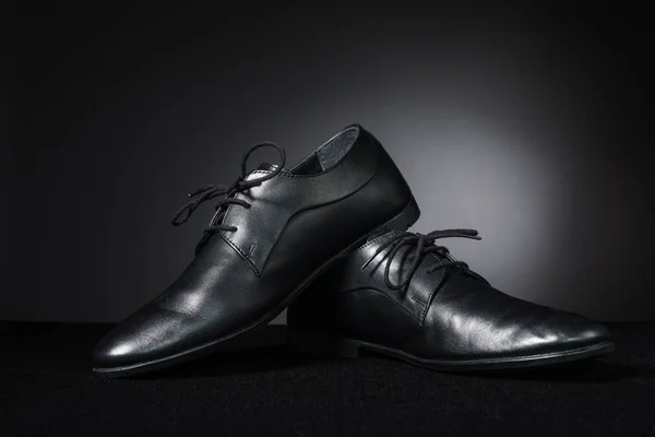 Black classic men\'s shoes on dark background.
