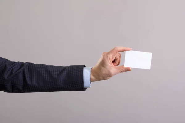 灰色の背景に空白カードを持ったビジネスマンの手 — ストック写真