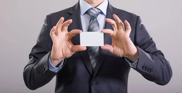 Hands of a businessman with a blank card on a gray background.