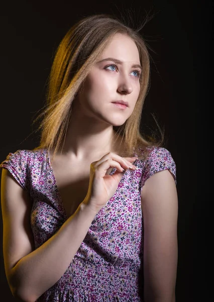 Portrait of a young woman on a black background.