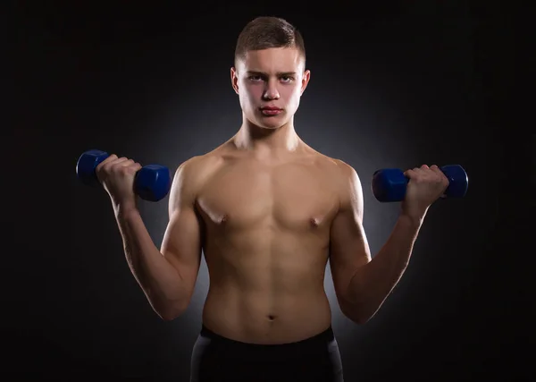 Joven Musculoso Con Mancuernas Sobre Fondo Oscuro — Foto de Stock