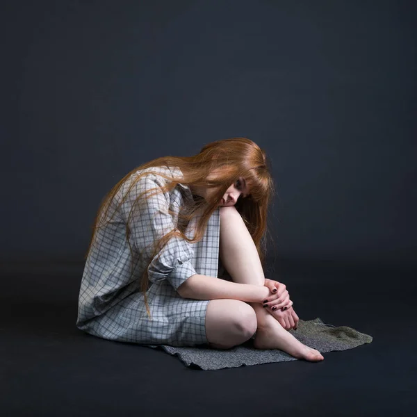 Uma Jovem Triste Ruiva Sentada Chão Isolada Fundo Escuro — Fotografia de Stock