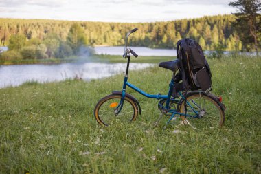 Bagajda yürüyüş sırt çantası bulunan bisiklet, doğada park edilebiyidir. Aktif bir yaşam tarzı kavramı.