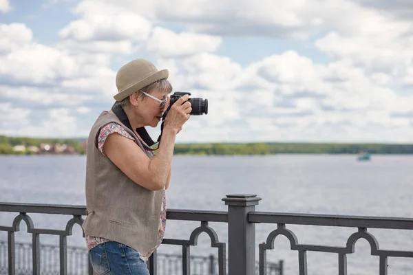 夏の市の堤防にカメラを持った高齢女性 高齢者のアクティブなライフスタイルの概念 — ストック写真