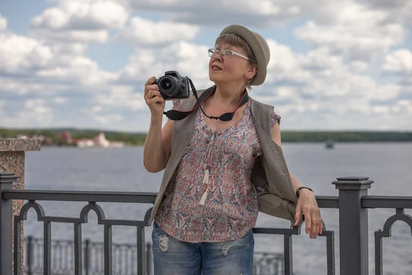 一位老妇人带着相机在城市堤坝上 老年人积极生活方式的概念 — 图库照片