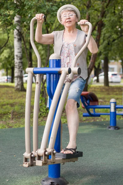 幸せな高齢女性がアクティブなライフスタイルをリードし 夏に市内公園でシミュレータを練習 — ストック写真