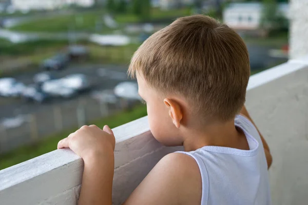 一个小男孩渴望地从公寓的逻辑上俯瞰着城市 幼儿孤立和孤独的概念 — 图库照片