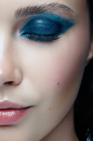 Closeup macro portrait of female face with eyes closed. Human woman half-face  with evening beauty makeup. Girl with perfect skin and blue-green eye shadows