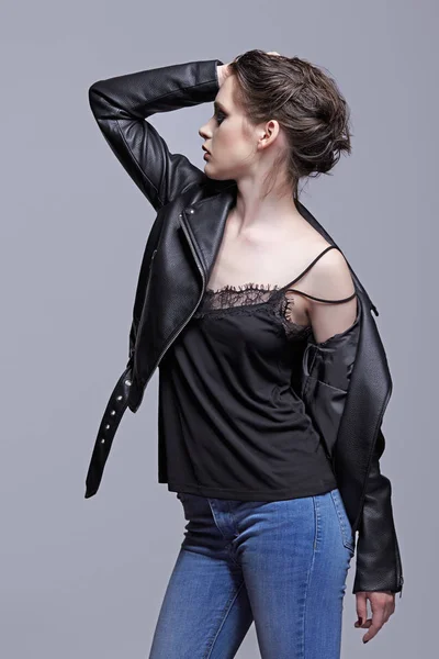 Portrait of female in black leather jacket with hand up. Woman with unusual beauty evening makeup. Girl with perfect skin and violet - black eye shadows make-up.